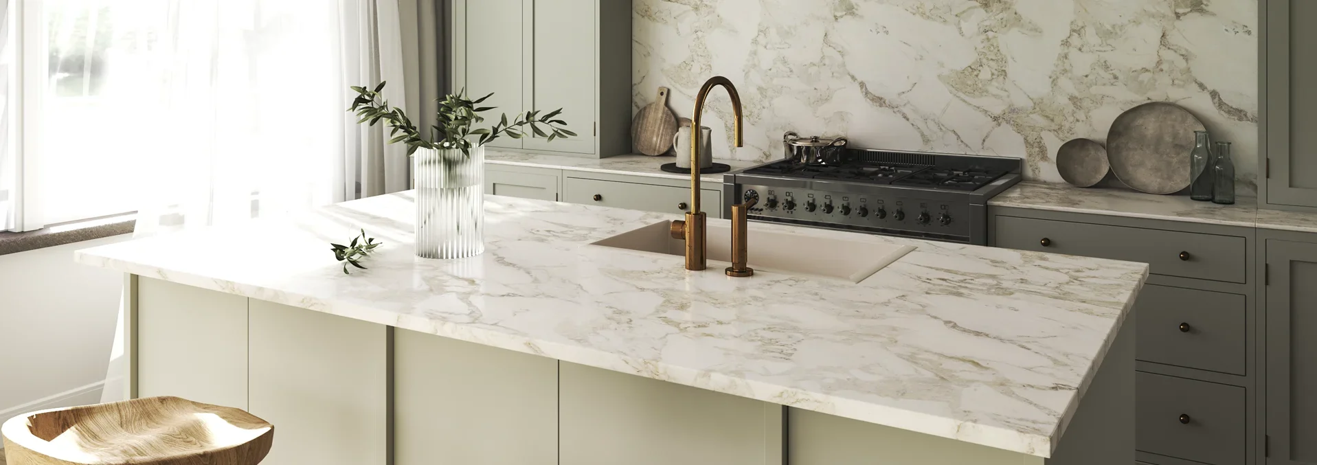 Modern kitchen with sage green cabinets, marble countertops and backsplash, three pendant lights, and black gas range.