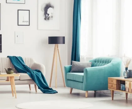 Phòng khách hiện đại với ghế xanh ngọc, sofa kem, đèn sàn gỗ, rèm xanh và tranh treo tường tối giản.