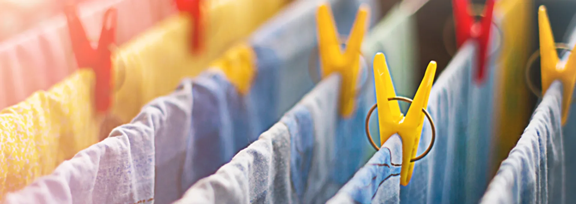 Colorful clothespegs holding wet laundry on a clothesline drying in sunlight.