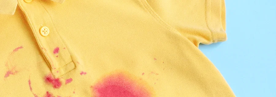 Yellow polo shirt with pink stains against a blue background.