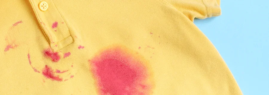 Yellow polo shirt with pink stains against a blue background.